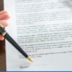 Person signing real estate contract with a pen.