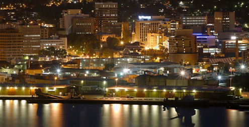View of Hobart from across the river at night. You can see the lights of the city reflecting on the water.