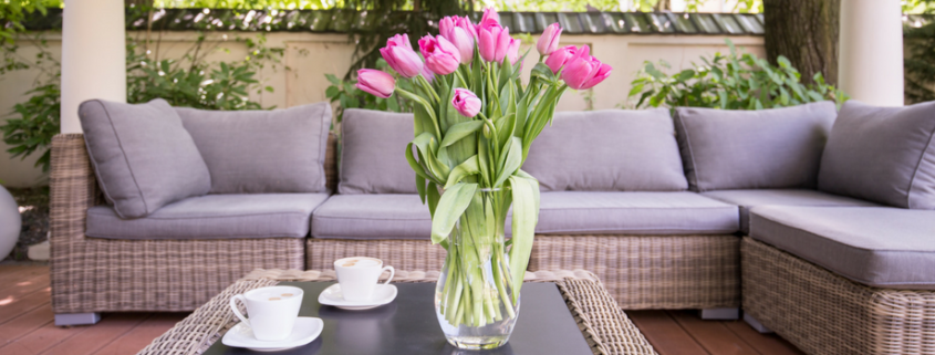 Modern patio, with grey patio set. Two cups on the table and a vase with flowers.